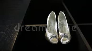 新娘婚礼漂亮的鞋子挂在一个黑色的<strong>柜子</strong>上，豪华的鞋跟特写